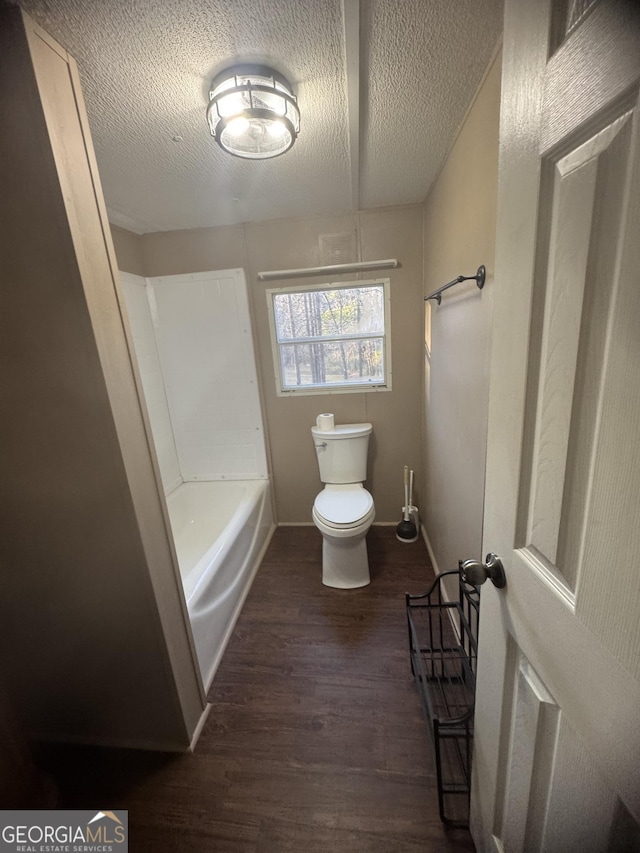 bathroom featuring hardwood / wood-style floors, a textured ceiling, toilet, and a bathtub