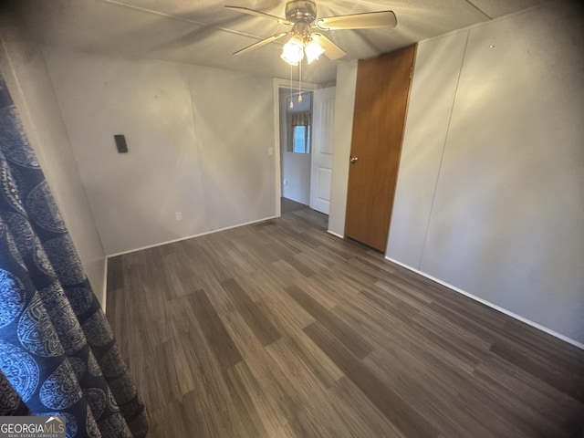 unfurnished room with ceiling fan and dark wood-type flooring