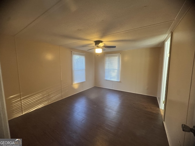 spare room with a textured ceiling, ceiling fan, and dark hardwood / wood-style floors