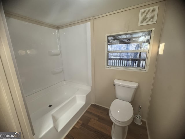 bathroom with hardwood / wood-style flooring, toilet, and shower / bathtub combination