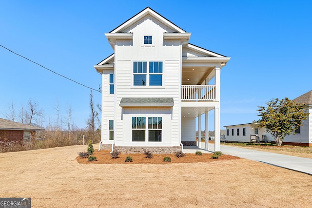 view of front of house featuring driveway, a carport, board and batten siding, and a balcony