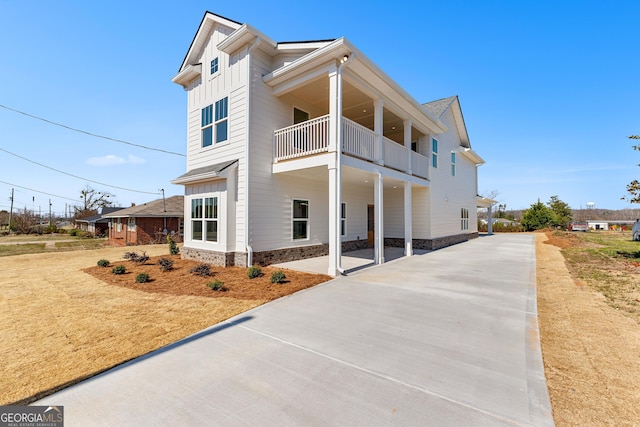 view of front of house with concrete driveway, board and batten siding, and a balcony