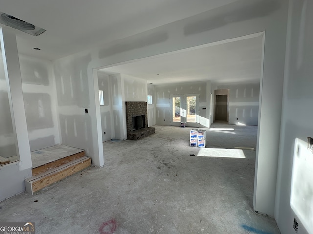 unfurnished living room featuring a fireplace and french doors