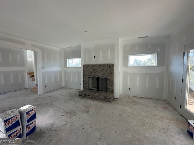 unfurnished living room with a wealth of natural light and a brick fireplace