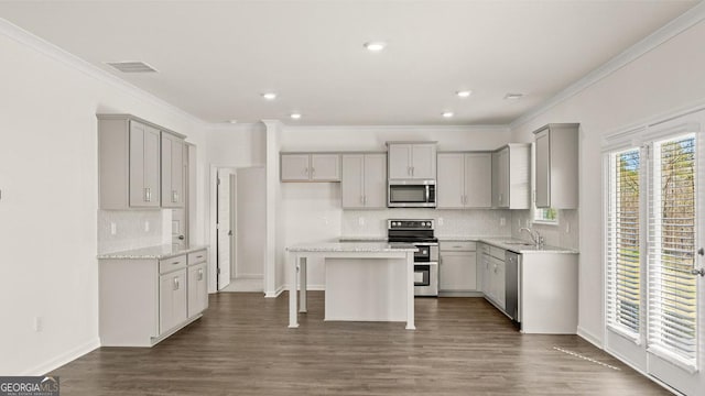 kitchen with ornamental molding, backsplash, gray cabinetry, stainless steel appliances, and a sink