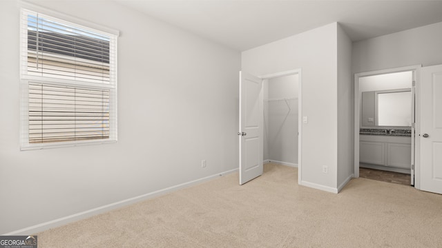 unfurnished bedroom with a closet, a walk in closet, light colored carpet, and multiple windows