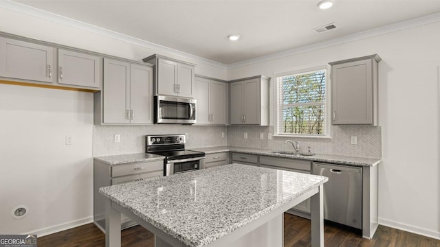 kitchen featuring stainless steel appliances, a kitchen breakfast bar, a sink, and gray cabinets