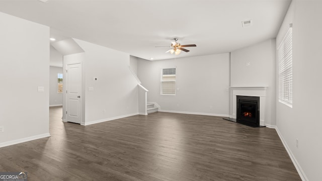 unfurnished living room with dark hardwood / wood-style flooring and ceiling fan