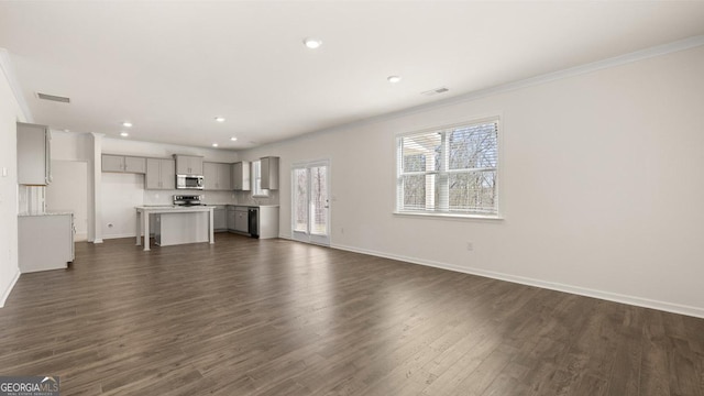 unfurnished living room with visible vents, baseboards, crown molding, and dark wood-style floors