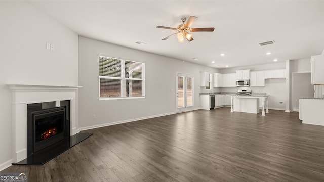 unfurnished living room featuring ceiling fan and dark wood-type flooring