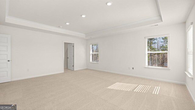spare room with a tray ceiling, baseboards, recessed lighting, and light carpet