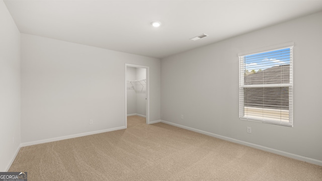 unfurnished bedroom featuring light carpet, a spacious closet, and a closet