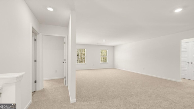 interior space featuring light colored carpet, baseboards, and recessed lighting
