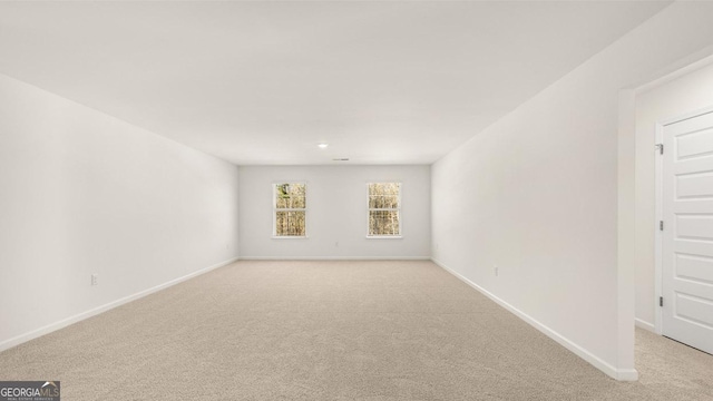 spare room with baseboards and light colored carpet