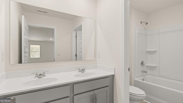 bathroom with double vanity, visible vents, a sink, and toilet