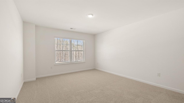 carpeted spare room featuring visible vents and baseboards