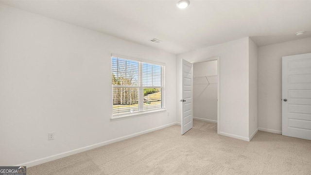 unfurnished bedroom with a closet, light colored carpet, baseboards, and visible vents