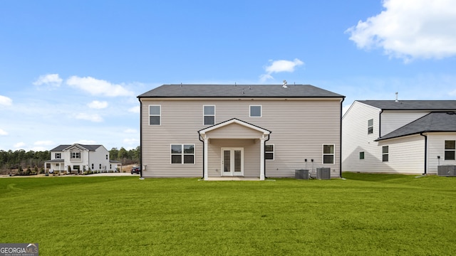 rear view of property featuring cooling unit, a yard, and french doors