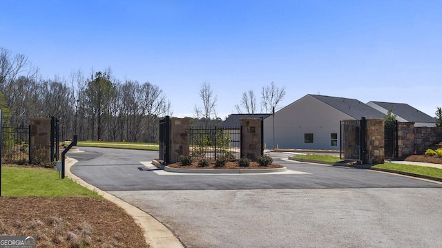view of road featuring a gated entry, curbs, and a gate