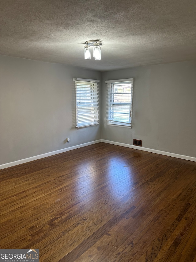 empty room with a textured ceiling and dark hardwood / wood-style floors