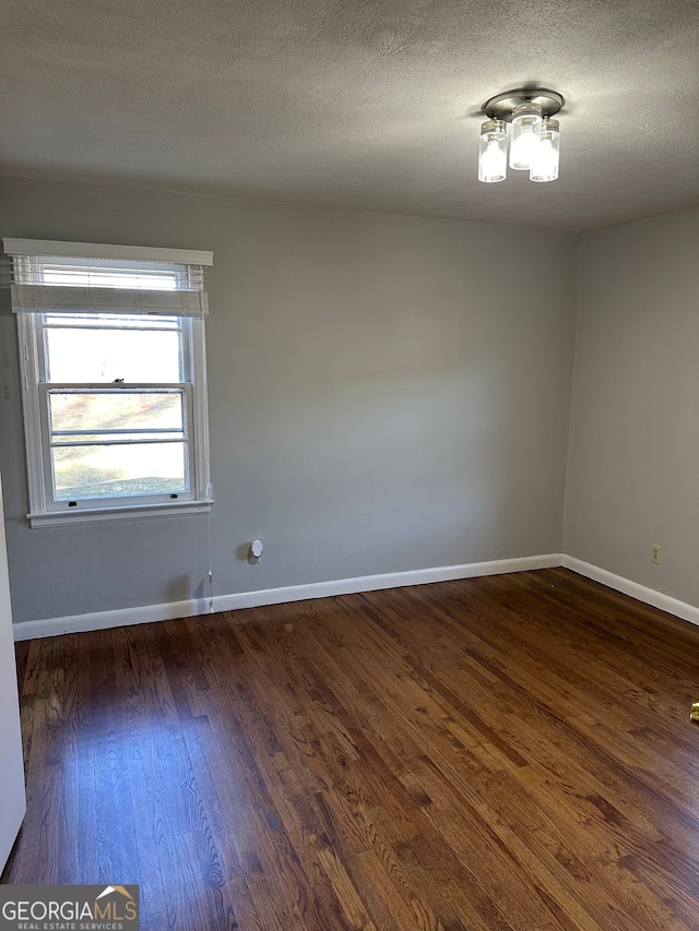 empty room with a textured ceiling and dark hardwood / wood-style floors