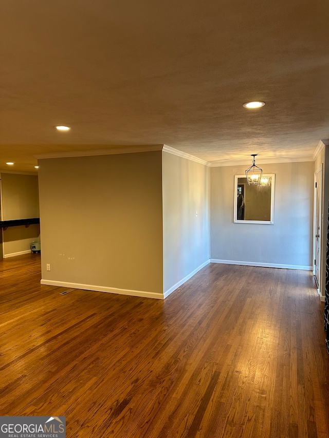 unfurnished room with a chandelier, dark hardwood / wood-style flooring, and ornamental molding