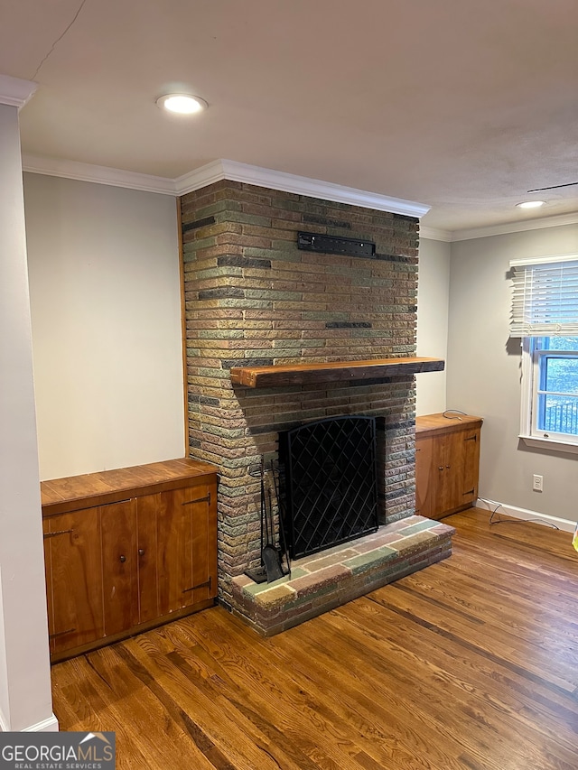 unfurnished living room featuring crown molding, light hardwood / wood-style flooring, and a brick fireplace