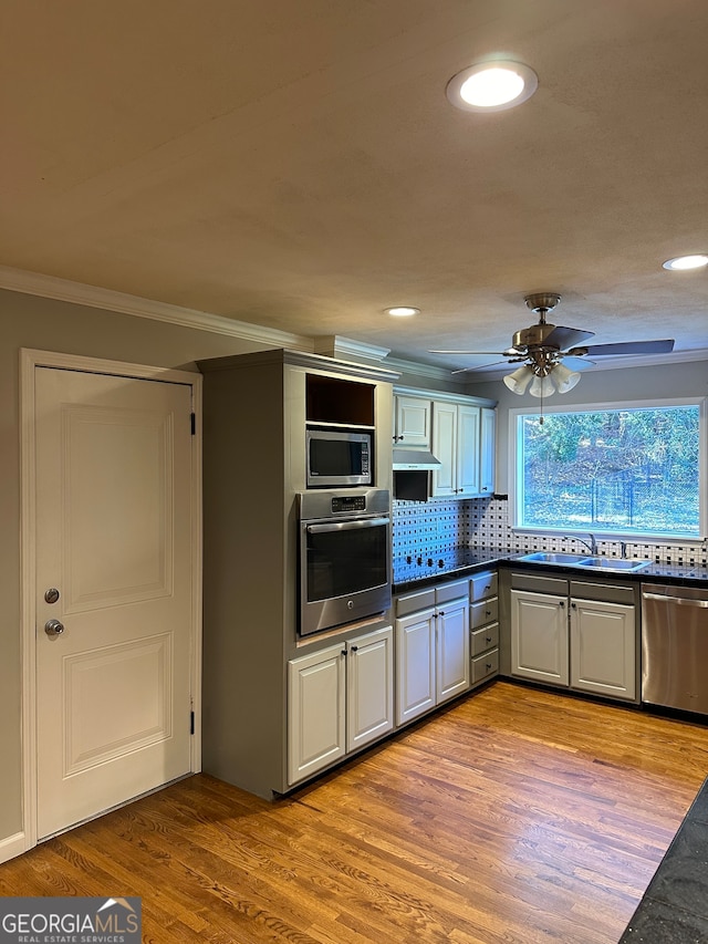 kitchen featuring light hardwood / wood-style flooring, ceiling fan, ornamental molding, tasteful backsplash, and stainless steel appliances