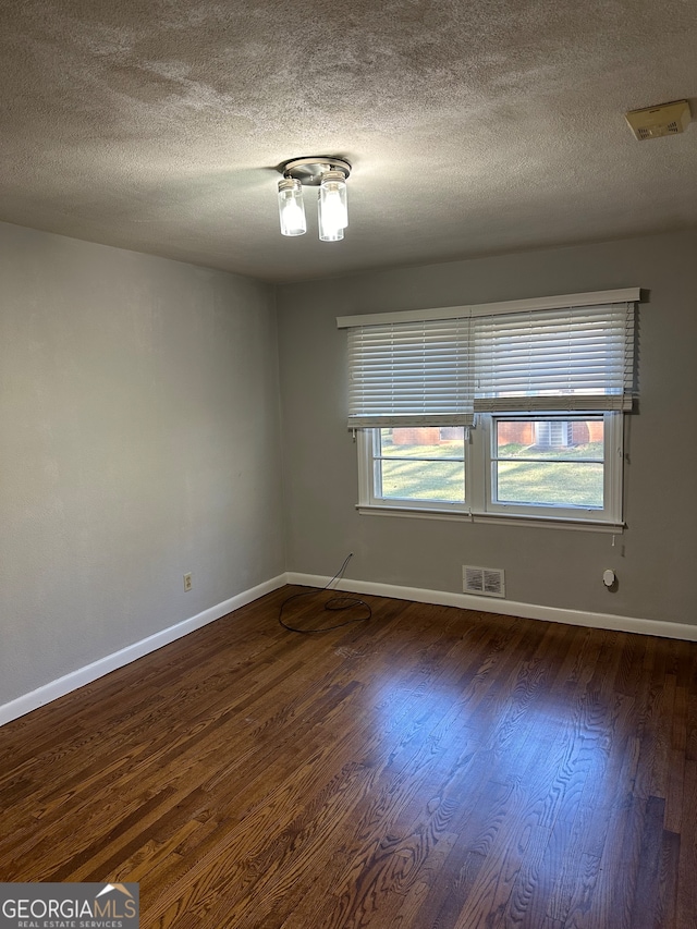 spare room with dark wood-type flooring and a textured ceiling