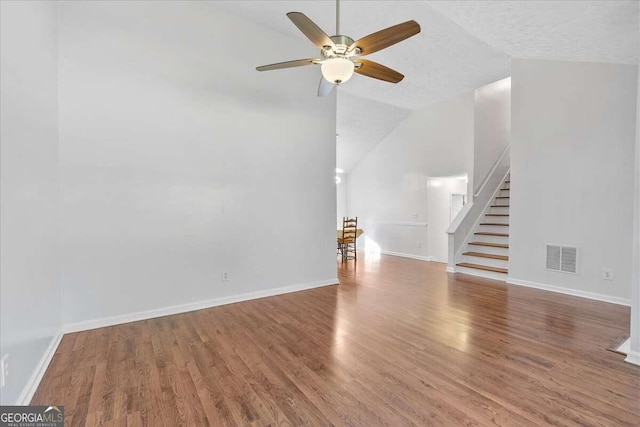 unfurnished living room featuring a textured ceiling, ceiling fan, hardwood / wood-style floors, and vaulted ceiling