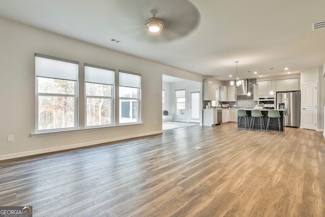 unfurnished living room featuring ceiling fan, a healthy amount of sunlight, and light hardwood / wood-style floors