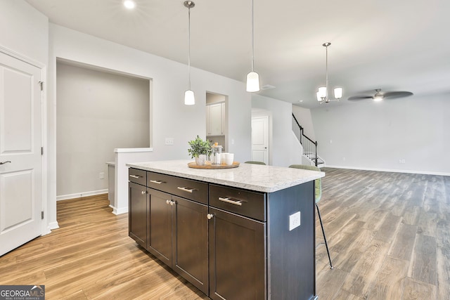 kitchen featuring a center island, a kitchen breakfast bar, decorative light fixtures, light hardwood / wood-style floors, and dark brown cabinetry