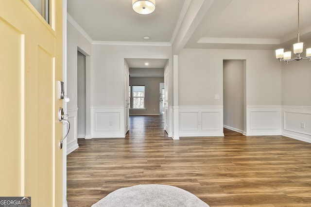 foyer entrance with a notable chandelier, crown molding, and dark wood-type flooring