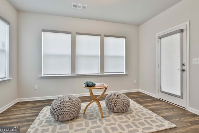 sitting room featuring dark wood-type flooring and a healthy amount of sunlight