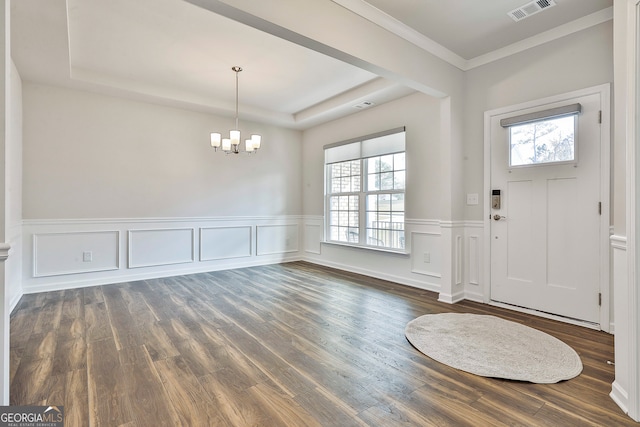 foyer with dark hardwood / wood-style flooring, ornamental molding, a wealth of natural light, and a chandelier