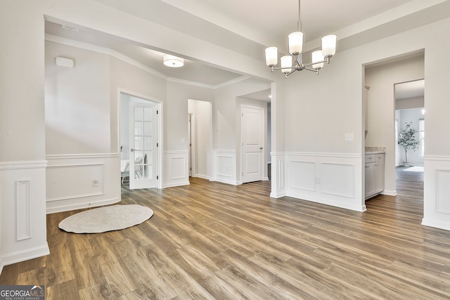 unfurnished dining area featuring hardwood / wood-style flooring, crown molding, and a chandelier