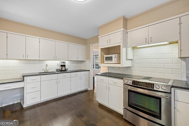 kitchen with white microwave, dark countertops, stainless steel range with electric stovetop, dark wood-style floors, and a sink