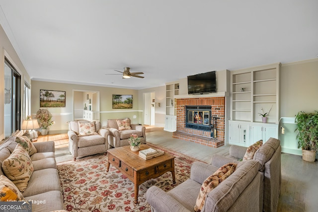 living area with wood finished floors, a fireplace, crown molding, baseboards, and ceiling fan