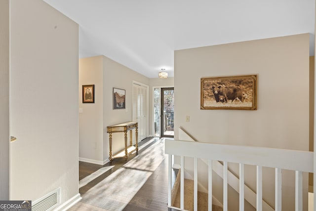 hallway featuring visible vents, dark wood-type flooring, and baseboards