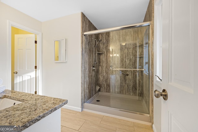 full bathroom featuring a stall shower, vanity, and baseboards