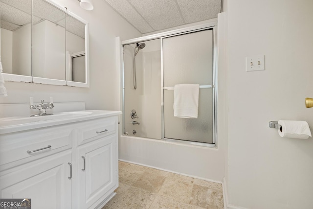 full bathroom with a drop ceiling, vanity, baseboards, and shower / bath combination with glass door