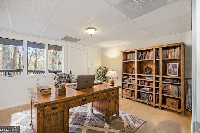 office area featuring baseboards, visible vents, a drop ceiling, and light carpet