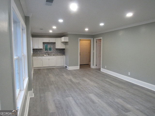 unfurnished living room with sink, crown molding, and light hardwood / wood-style flooring