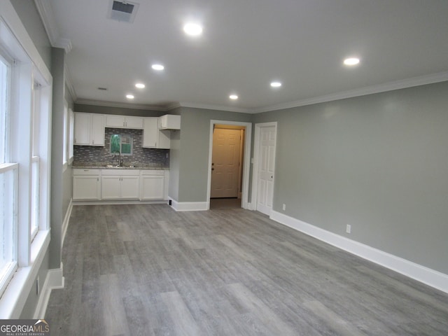 unfurnished living room with crown molding, sink, and light hardwood / wood-style floors