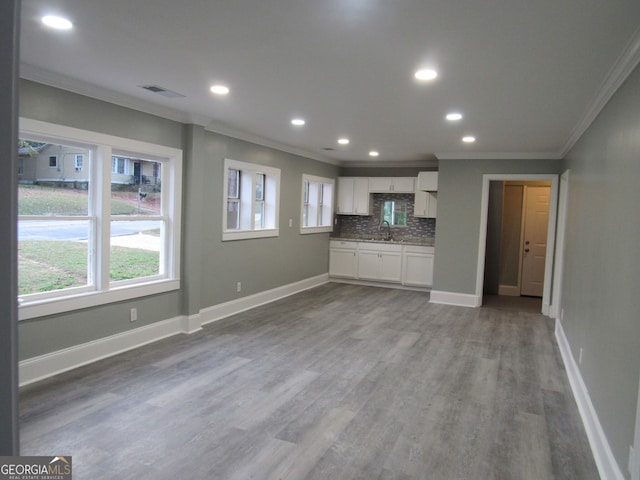 kitchen featuring sink, hardwood / wood-style flooring, decorative backsplash, ornamental molding, and white cabinetry