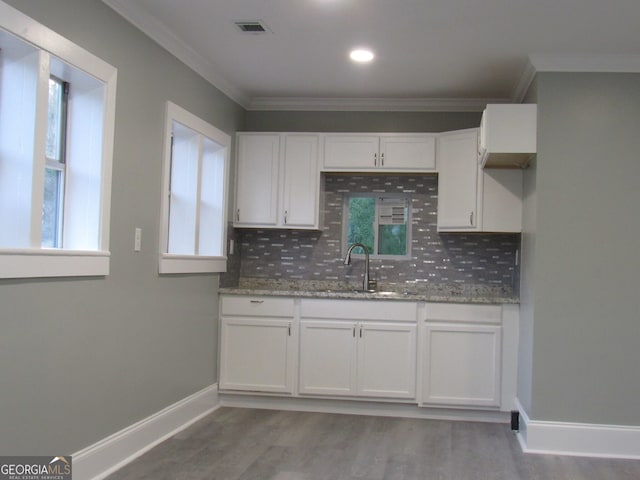 kitchen with backsplash, light stone counters, sink, and white cabinets