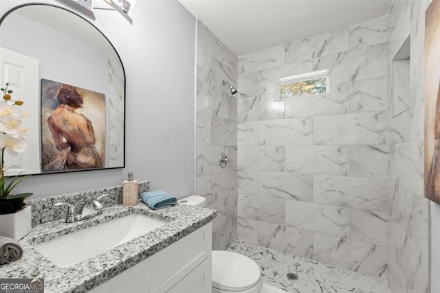 bathroom featuring tiled shower, vanity, and toilet