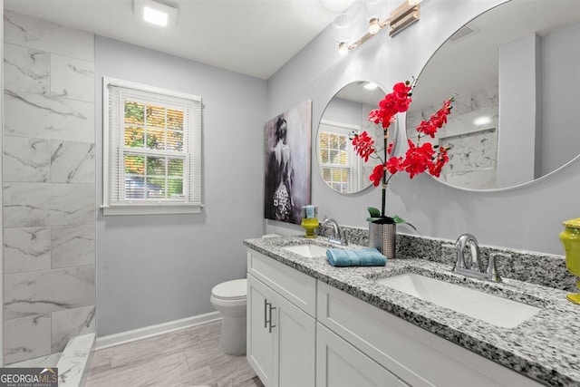 bathroom with vanity, toilet, and tiled shower