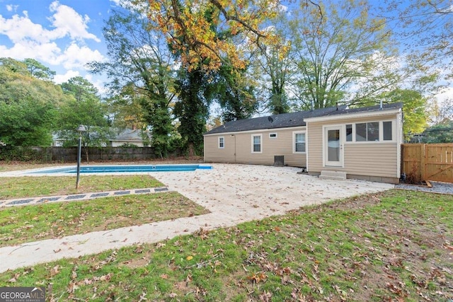 rear view of house featuring a fenced in pool and a lawn