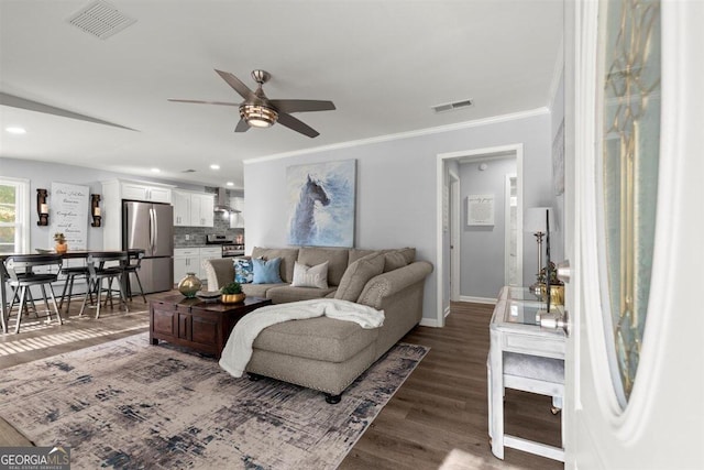 living room with dark hardwood / wood-style floors, ceiling fan, and ornamental molding